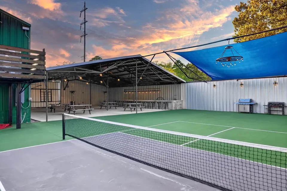 The pickleball court at sunset, with the covered pavilion and its string lights behind it
