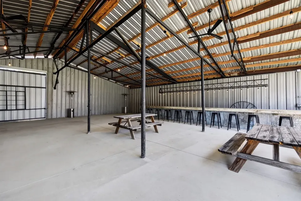 Inside the covered pavilion, under steel and timber roof framing