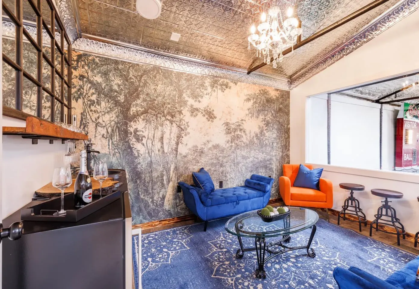 The lounge, with blue velvet seating, a tin ceiling, a chandelier and a window onto the baseball scoreboard