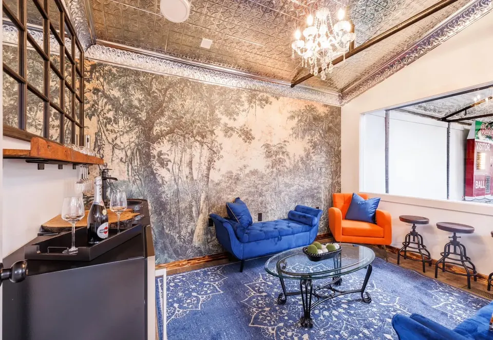 The lounge, with blue velvet seating, a tin ceiling, a chandelier and a window onto the baseball scoreboard